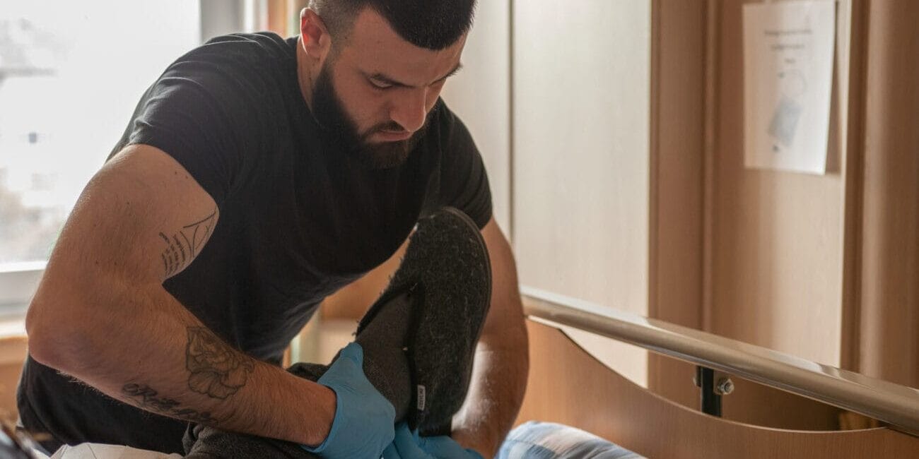 Photos d'un aide familial aidant un bénéficiaire de la CSD Bruxelles à mettre ses chaussures