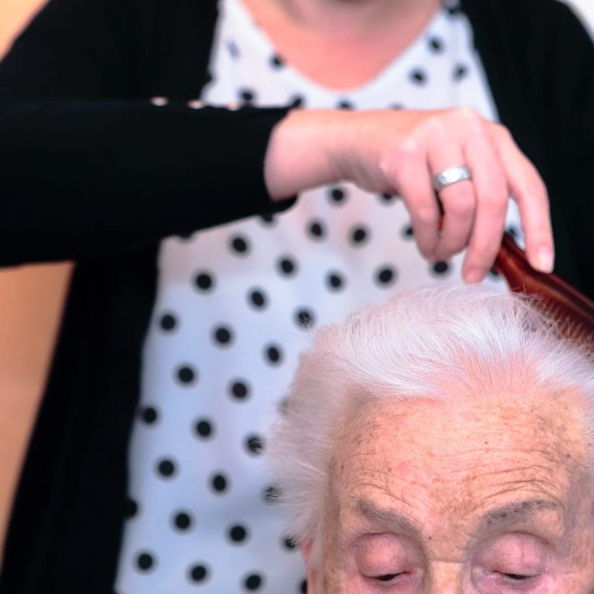 Photo d'une aide familial de la CSD Bruxelles en train de coiffer une bénéficaire